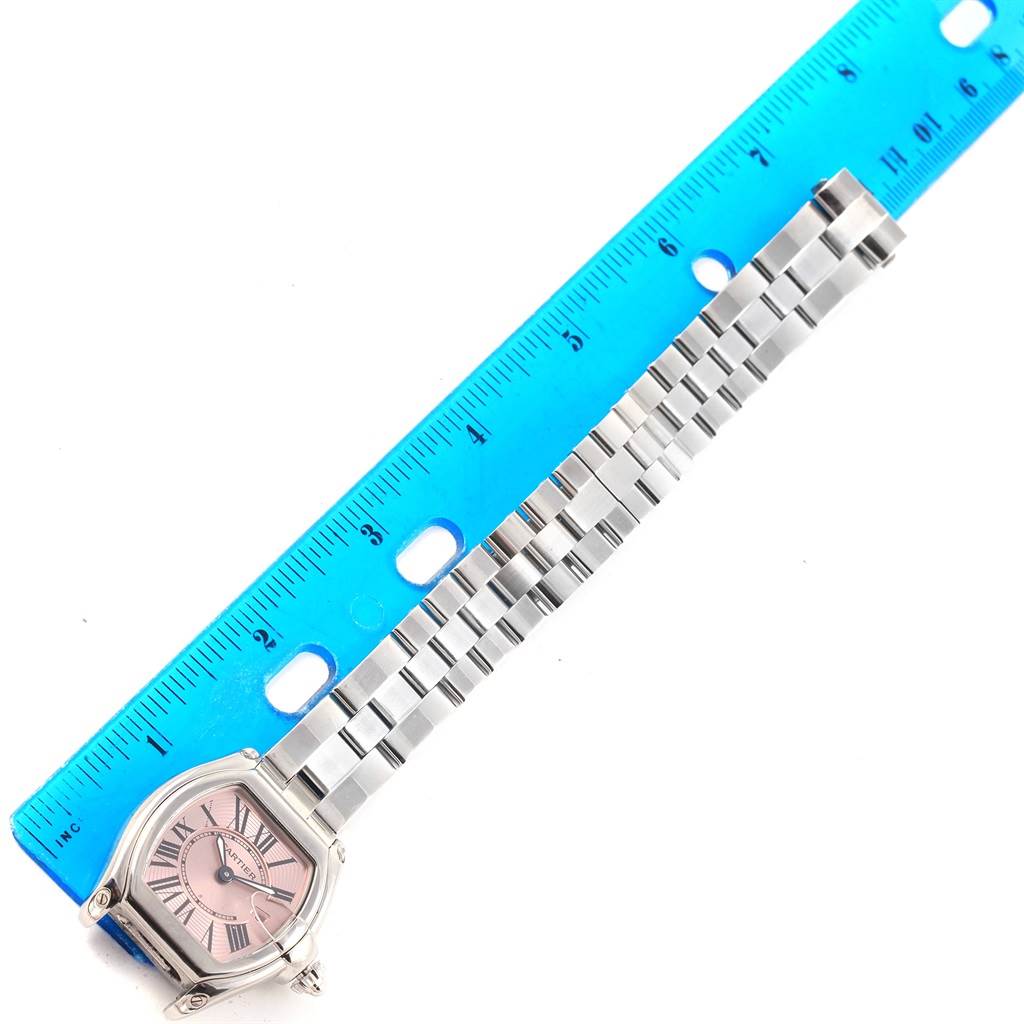 The image shows a Cartier Roadster W62017V3 Women
s Stainless Steel Pink Dial W62017V3 Women
s Stainless Steel Pink Dial watch at an overhead angle, featuring the watch face and full bracelet next to a blue ruler for scale.
