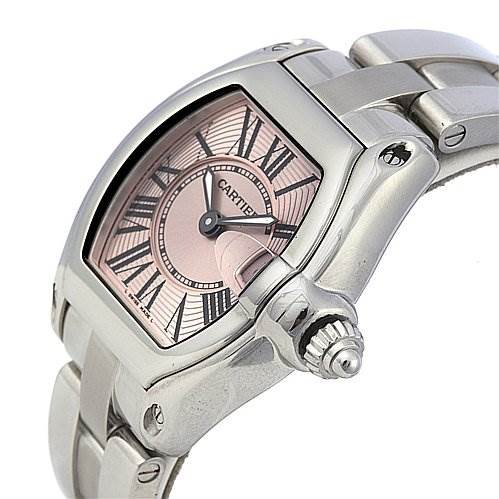 The image shows a side-angle view of a Cartier Roadster W62017V3 Women
s Stainless Steel Pink Dial W62017V3 Women
s Stainless Steel Pink Dial watch, highlighting the pink dial, Roman numerals, crown, and stainless steel bracelet.