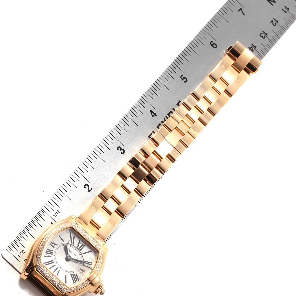The Cartier Roadster WE5001X1 Women's Yellow Gold Silver Dial WE5001X1 Women's Yellow Gold Silver Dial model watch is shown flat, displaying the face, some links of the metal bracelet, and a measuring ruler for scale.