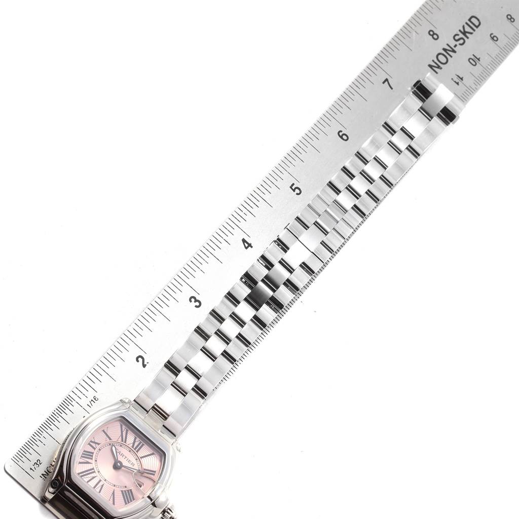 The image shows a Cartier Roadster W62017V3 Women
s Stainless Steel Pink Dial W62017V3 Women
s Stainless Steel Pink Dial watch placed alongside a ruler, highlighting its face and metallic bracelet.