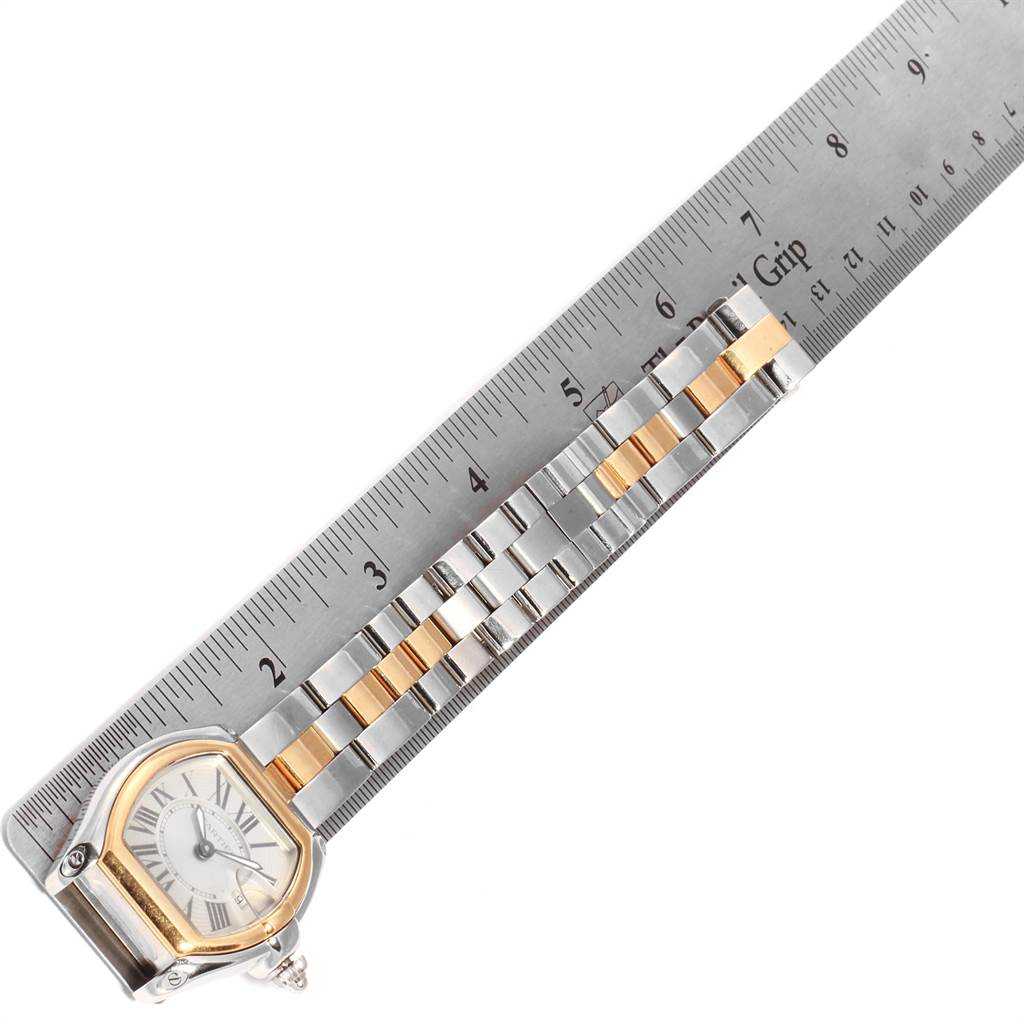 The Cartier Roadster W62026Y4 Women's Steel and Gold (two tone) Silver Dial W62026Y4 Women's Steel and Gold (two tone) Silver Dial watch is shown from a top-down angle, displaying its dial and part of the metal and gold link bracelet alongside a ruler.