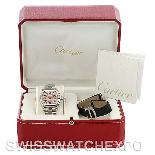This image shows a Cartier Roadster W62017V3 Women's Stainless Steel Pink Dial W62017V3 Women's Stainless Steel Pink Dial watch with a pink dial, an additional strap, and a booklet, all placed in an open red Cartier box.