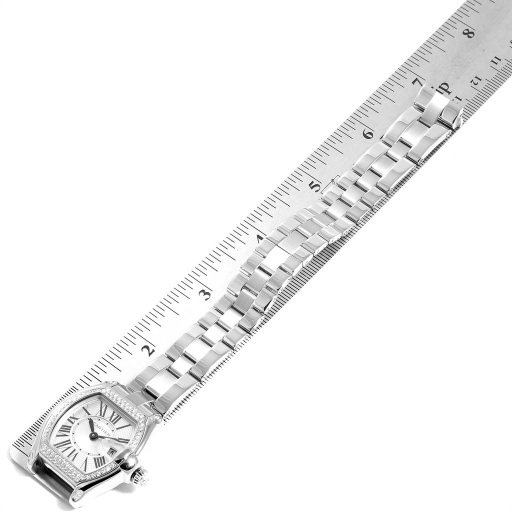 The image shows a Cartier Roadster WE5002X2 Women's White Gold Silver Dial WE5002X2 Women's White Gold Silver Dial model watch lying flat next to a metal ruler, highlighting the watch face and bracelet.