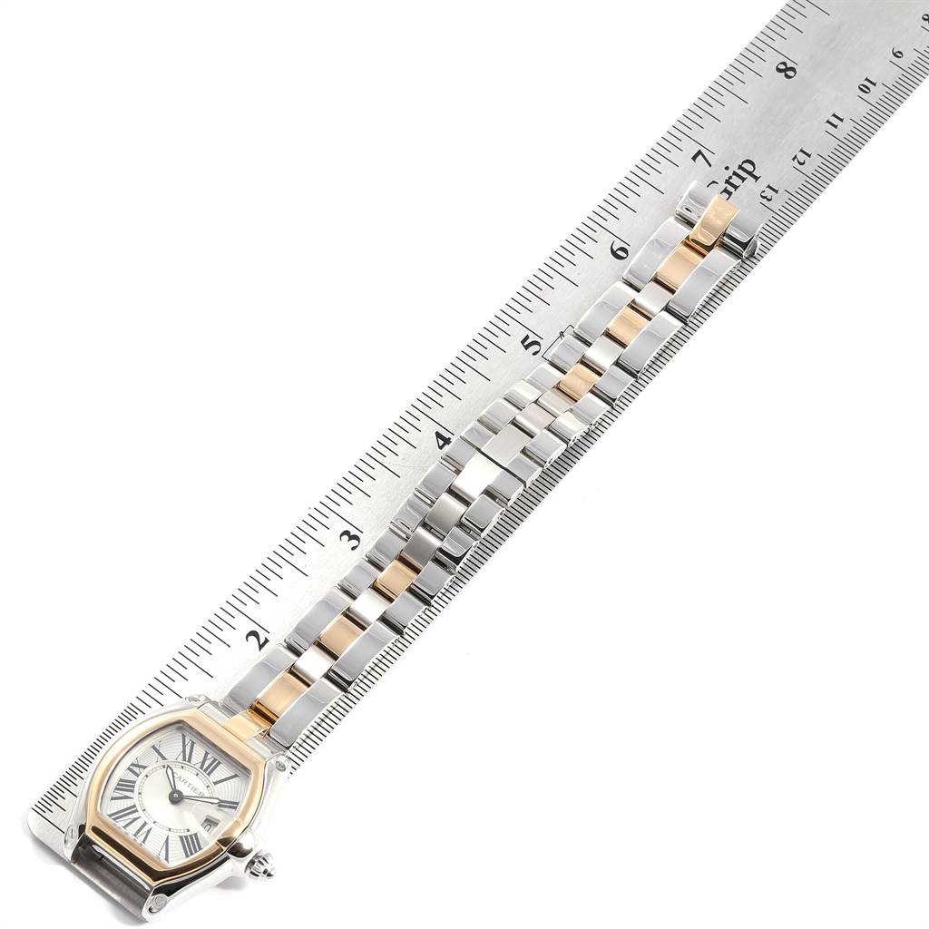 The Cartier Roadster W62026Y4 Women's Steel and Gold (two tone) Silver Dial W62026Y4 Women's Steel and Gold (two tone) Silver Dial watch is shown at an angle that highlights the face, bezel, and bracelet alongside a ruler for scale.