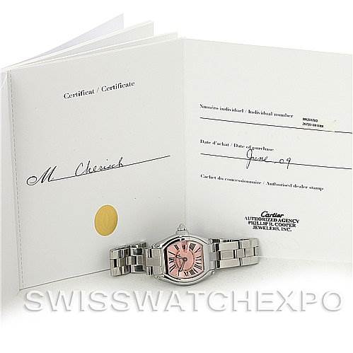 The image shows a Cartier Roadster W62017V3 Women's Stainless Steel Pink Dial W62017V3 Women's Stainless Steel Pink Dial watch lying in front of an open certificate booklet, viewed from the front at an angle.