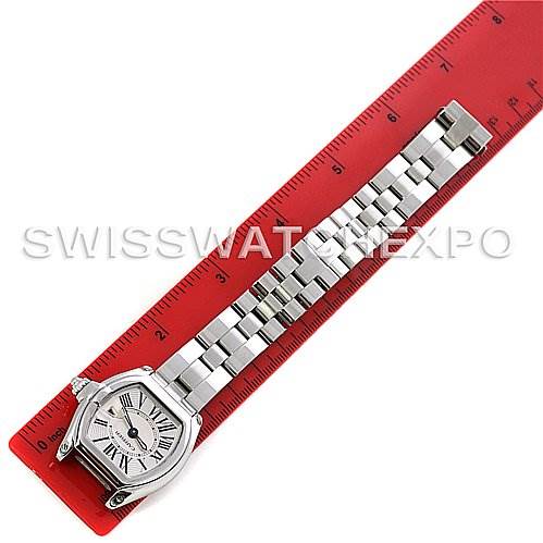 The Cartier Roadster W62016V3 Women
s Stainless Steel Silver Dial W62016V3 Women
s Stainless Steel Silver Dial watch is shown from above, displaying the face and metal bracelet laid alongside a red ruler.