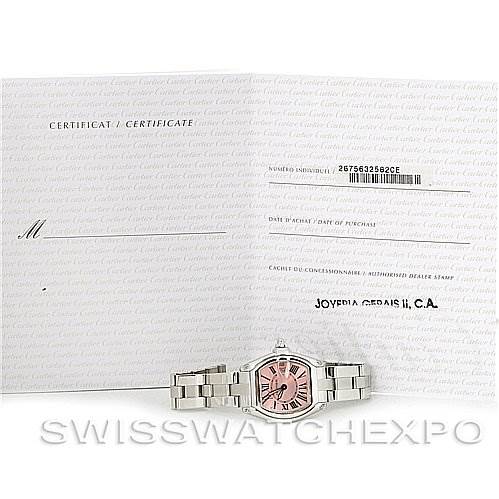 The image shows a Cartier Roadster W62017V3 Women's Stainless Steel Pink Dial W62017V3 Women's Stainless Steel Pink Dial watch with a pink dial and a metal band, alongside its certificate of authenticity.