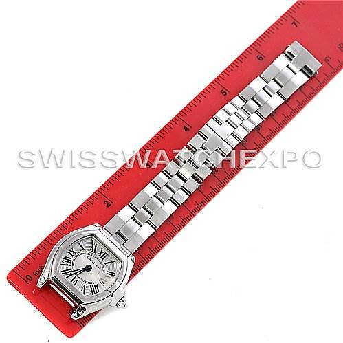The Cartier Roadster W62016V3 Women
s Stainless Steel Silver Dial W62016V3 Women
s Stainless Steel Silver Dial watch is shown from a top-down angle, displaying the watch face, case, and entire bracelet on a red ruler.