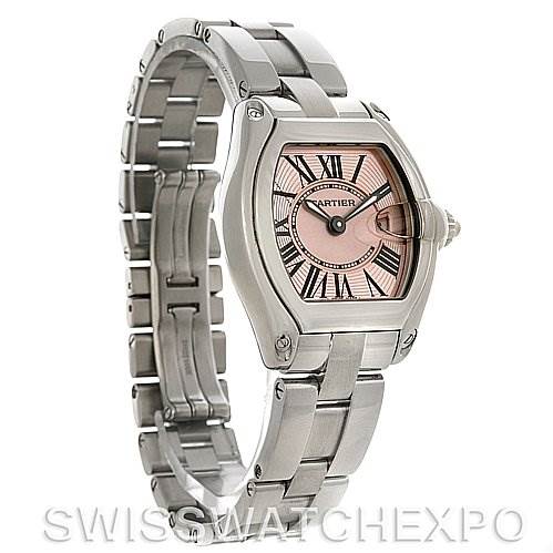 The image shows a Cartier Roadster W62017V3 Women
s Stainless Steel Pink Dial W62017V3 Women
s Stainless Steel Pink Dial watch from an angled side view, highlighting its pink dial, stainless steel case, and bracelet.