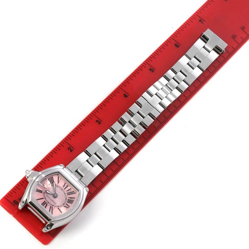 The Cartier Roadster W62043V3 Women's Stainless Steel Pink Dial W62043V3 Women's Stainless Steel Pink Dial watch is shown from a top-down angle, displaying the face, case, and metal bracelet alongside a red ruler.