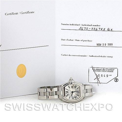 The image shows a Cartier Roadster W62016V3 Women
s Stainless Steel Silver Dial W62016V3 Women
s Stainless Steel Silver Dial watch placed on its side, along with its certificate of Best Quality
ity.