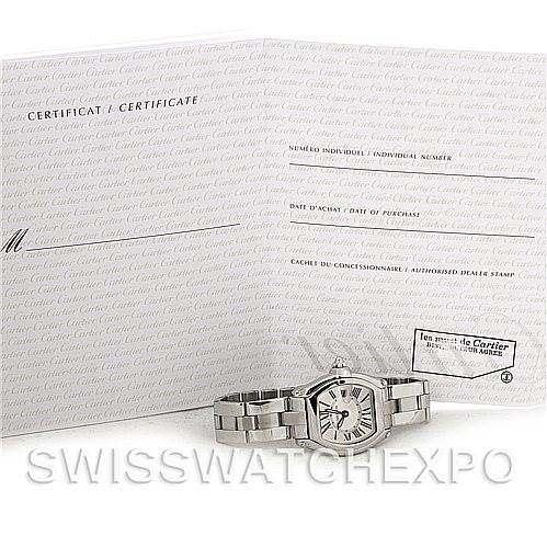 The image shows a Cartier Roadster W62016V3 Women
s Stainless Steel Silver Dial W62016V3 Women
s Stainless Steel Silver Dial watch lying flat with its certificate of Best Quality
ity spread open behind it.
