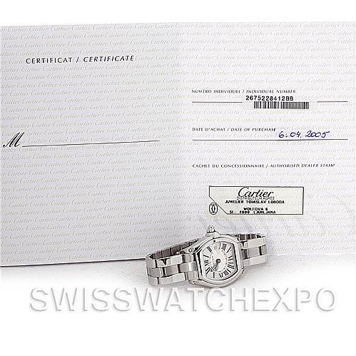 The image shows a Cartier Roadster W62016V3 Women
s Stainless Steel Silver Dial W62016V3 Women
s Stainless Steel Silver Dial watch placed in front of its certificate and documentation.