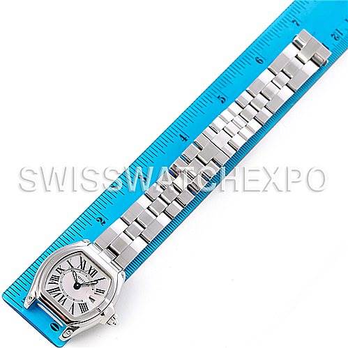 The image shows a top-down view of a Cartier Roadster W62016V3 Women
s Stainless Steel Silver Dial W62016V3 Women
s Stainless Steel Silver Dial watch laid out next to a blue measuring ruler.