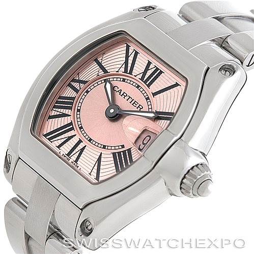 The Cartier Roadster W62017V3 Women's Stainless Steel Pink Dial W62017V3 Women's Stainless Steel Pink Dial watch is shown at an angle, highlighting its pink dial, Roman numerals, and partial stainless steel bracelet.