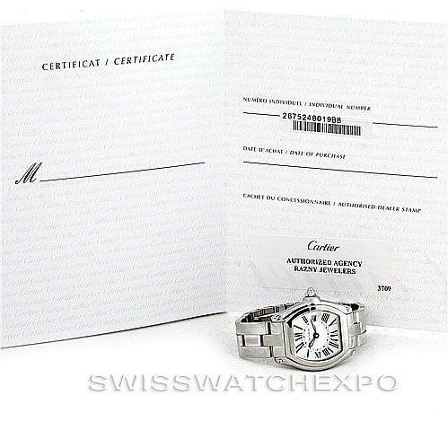 The image shows a Cartier Roadster W62016V3 Women's Stainless Steel Silver Dial W62016V3 Women's Stainless Steel Silver Dial watch laying flat with its certificate papers and an authorized dealer stamp in the background.