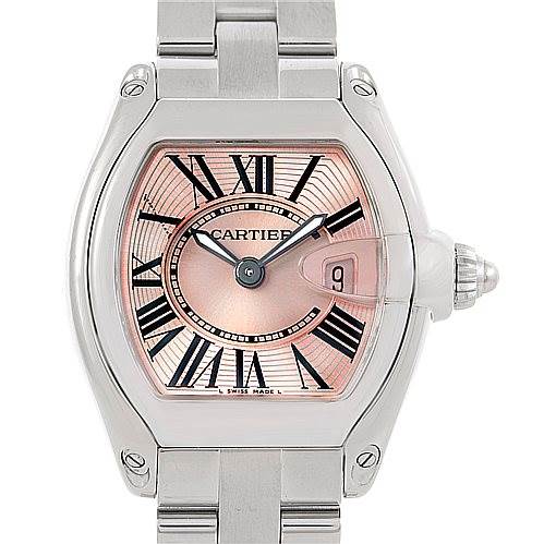 The image shows a frontal view of a Cartier Roadster W62017V3 Women's Stainless Steel Pink Dial W62017V3 Women's Stainless Steel Pink Dial watch, highlighting its pink dial, Roman numerals, and date window.