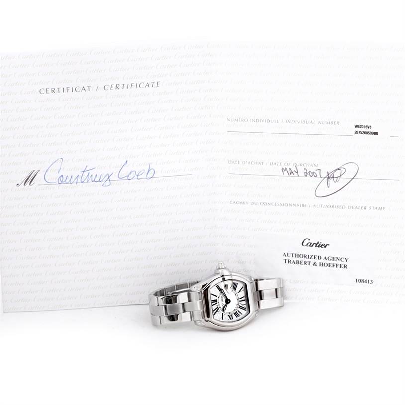 The image shows a Cartier Roadster W62016V3 Women's Stainless Steel Silver Dial W62016V3 Women's Stainless Steel Silver Dial watch lying flat with its certificate of authenticity displayed in the background.