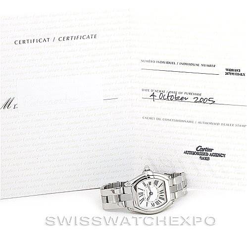The image shows a Cartier Roadster W62016V3 Women's Stainless Steel Silver Dial W62016V3 Women's Stainless Steel Silver Dial watch lying flat next to its certificate and purchase documents.