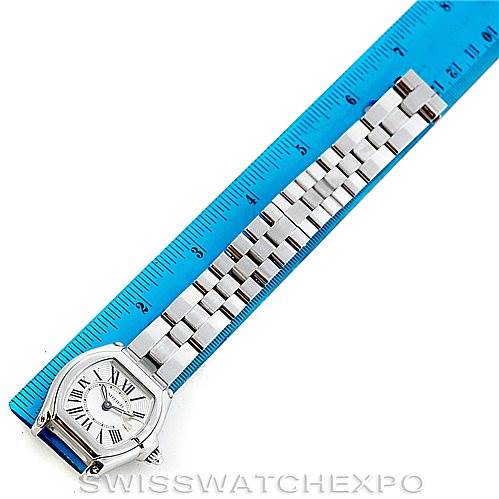 The image shows a Cartier Roadster W62016V3 Women's Stainless Steel Silver Dial W62016V3 Women's Stainless Steel Silver Dial watch angled top-down, featuring the face and a fully extended metal bracelet against a blue ruler.