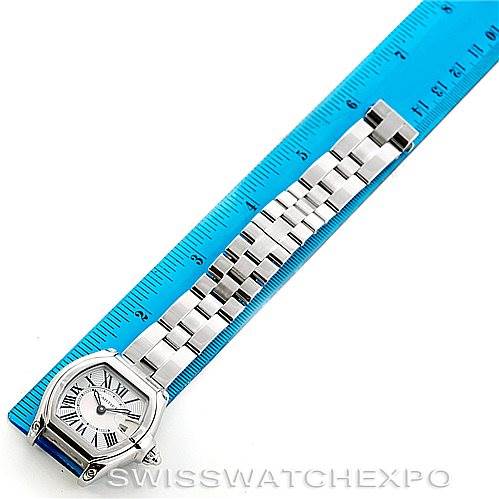 The Cartier Roadster W62016V3 Women's Stainless Steel Silver Dial W62016V3 Women's Stainless Steel Silver Dial watch is shown from a top-down angle, displaying the face and metal bracelet laid beside a ruler.