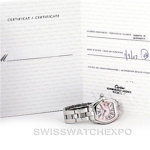 The image shows a Cartier Roadster W62017V3 Women's Stainless Steel Pink Dial W62017V3 Women's Stainless Steel Pink Dial watch lying flat with its certificate of authenticity displayed behind it.