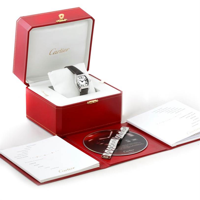 The Cartier Roadster W62016V3 Women's Stainless Steel Silver Dial W62016V3 Women's Stainless Steel Silver Dial watch is shown at a front angle, displaying its face inside a red box, along with accessories including a CD, booklet, and metal bracelet.