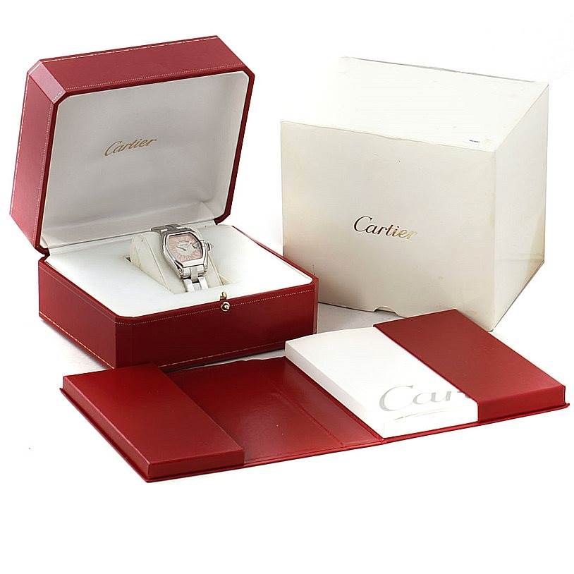 The image shows the Cartier Roadster W62054V3 Women's Stainless Steel Pink Dial W62054V3 Women's Stainless Steel Pink Dial watch in its open box with additional packaging and documents.