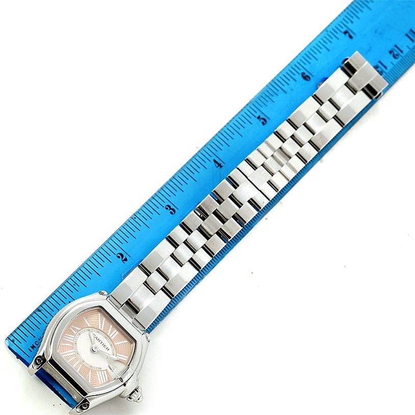 The image shows the face and bracelet of a Cartier Roadster W62054V3 Women's Stainless Steel Pink Dial W62054V3 Women's Stainless Steel Pink Dial watch at an angle, measured against a blue ruler.