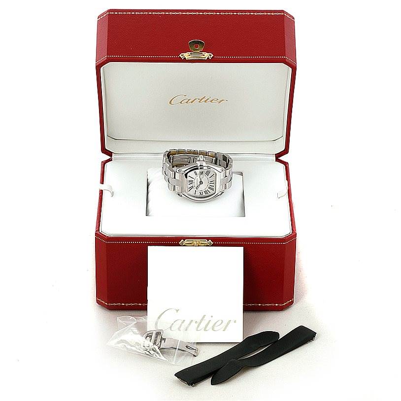 The Cartier Roadster W62016V3 Women's Stainless Steel Silver Dial W62016V3 Women's Stainless Steel Silver Dial watch is displayed in an open red Cartier box, with additional straps and accessories visible in front.