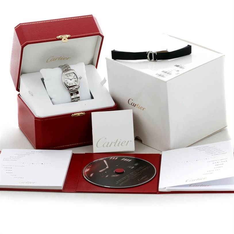 This image shows a Cartier Roadster W62016V3 Women's Stainless Steel Silver Dial W62016V3 Women's Stainless Steel Silver Dial watch in its open box with accompanying accessories, manual, and CD.