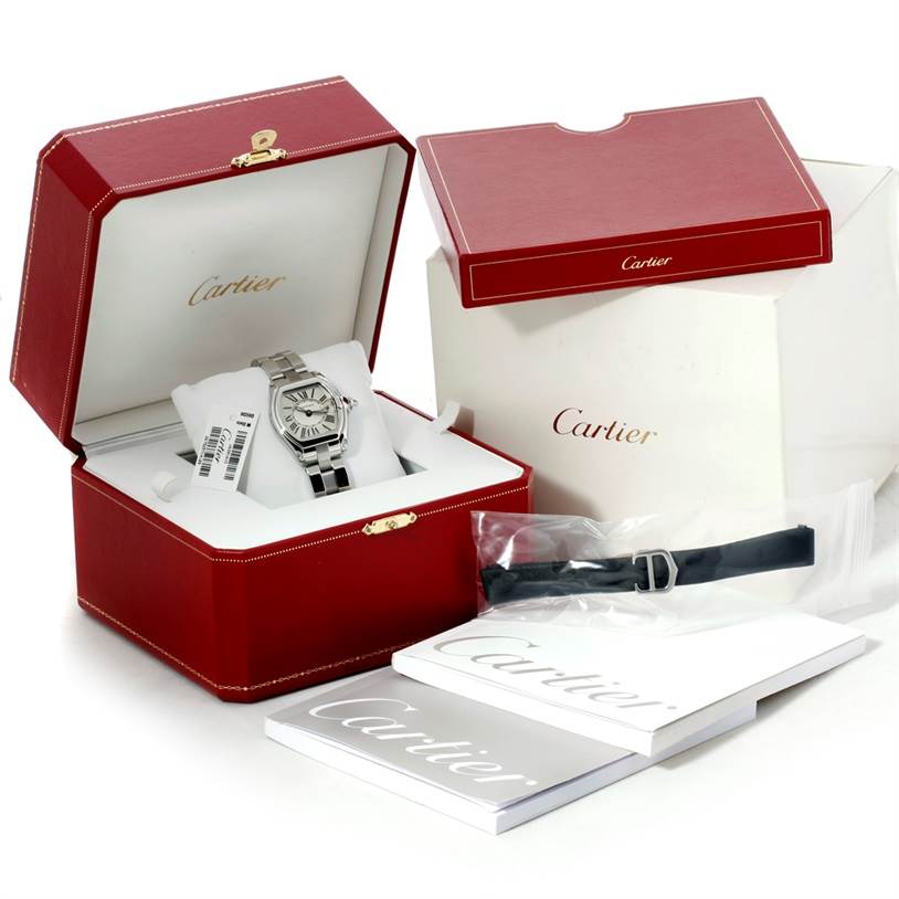 The Cartier Roadster W62016V3 Women's Stainless Steel Silver Dial W62016V3 Women's Stainless Steel Silver Dial watch is displayed in an open red box with additional packaging, a booklet, and a strap beside it.