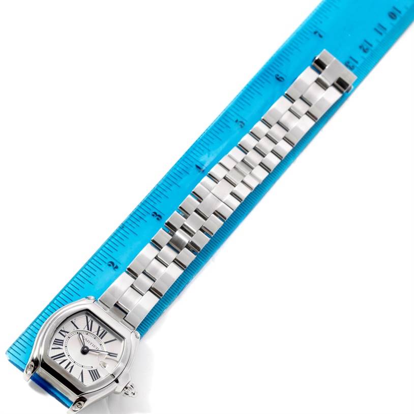 The Cartier Roadster W62016V3 Women's Stainless Steel Silver Dial W62016V3 Women's Stainless Steel Silver Dial watch is shown from the top view, highlighting the face and linked bracelet, placed alongside a blue ruler.