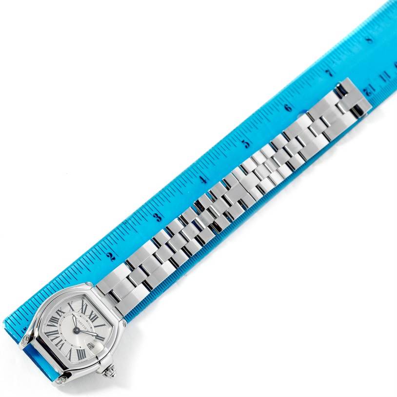 The image shows a top-down view of a Cartier Roadster W62016V3 Women's Stainless Steel Silver Dial W62016V3 Women's Stainless Steel Silver Dial watch, highlighting its face and metal bracelet alongside a blue ruler.