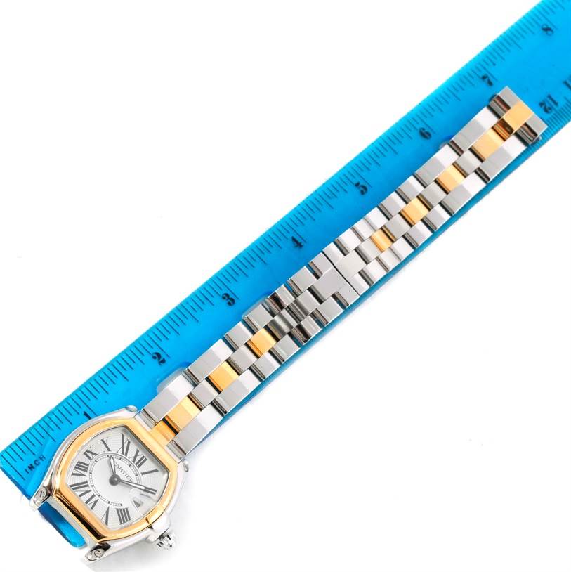 A Cartier Roadster W62026Y4 Women's Steel and Gold (two tone) Silver Dial W62026Y4 Women's Steel and Gold (two tone) Silver Dial watch is shown from a top-down angle, displaying its face and bi-color metal bracelet next to a ruler.
