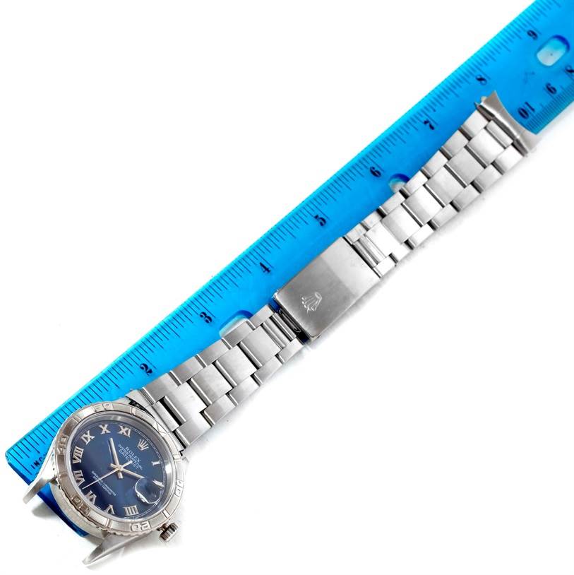 The Rolex Turn-o-Graph 16264 Men's Stainless Steel Blue Dial 16264 Men's Stainless Steel Blue Dial watch is shown lying flat with its face, bezel, bracelet, and clasp visible, alongside a ruler for scale.