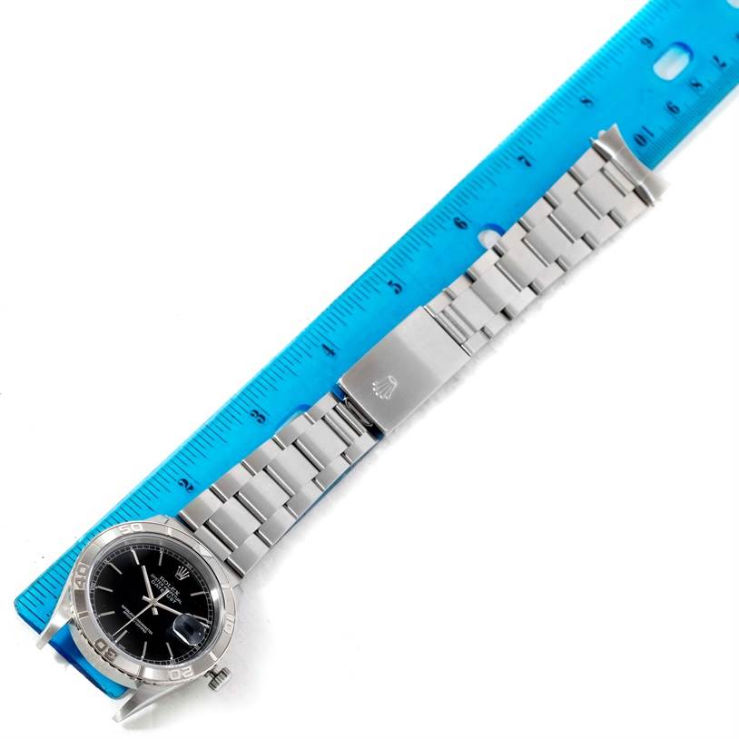 The image shows the entire Rolex Turn-o-Graph 16264 Men's Stainless Steel Black Dial 16264 Men's Stainless Steel Black Dial watch, including its bezel, dial, bracelet, and clasp, placed next to a blue ruler.