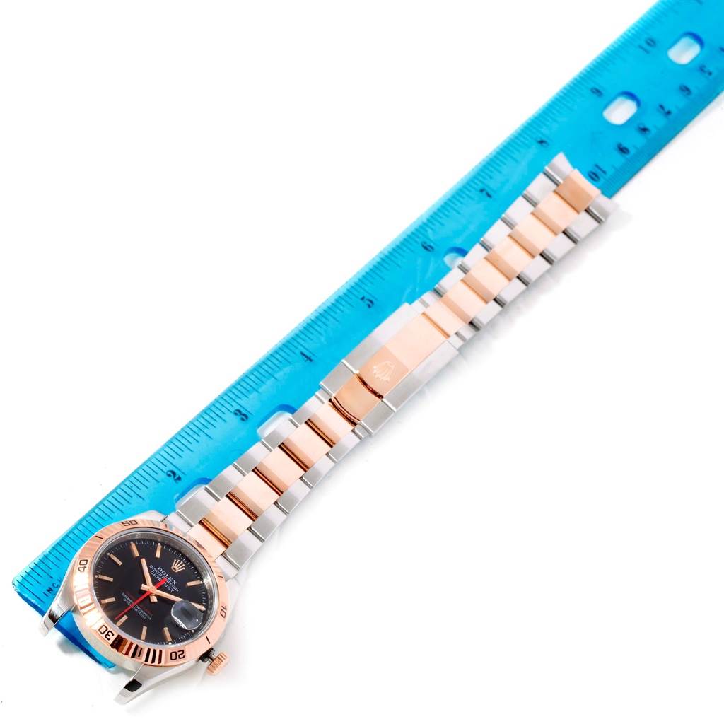 The image shows a full view of the Rolex Turn-o-Graph 116261 Men's Stainless Steel Black Dial 116261 Men's Stainless Steel Black Dial watch with its band and a ruler for scale.