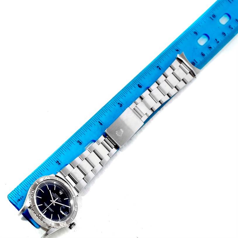 The Rolex Turn-o-Graph 16264 Men's Stainless Steel Black Dial 16264 Men's Stainless Steel Black Dial watch is shown from a top-down angle, displaying its face, bezel, and bracelet alongside a ruler.