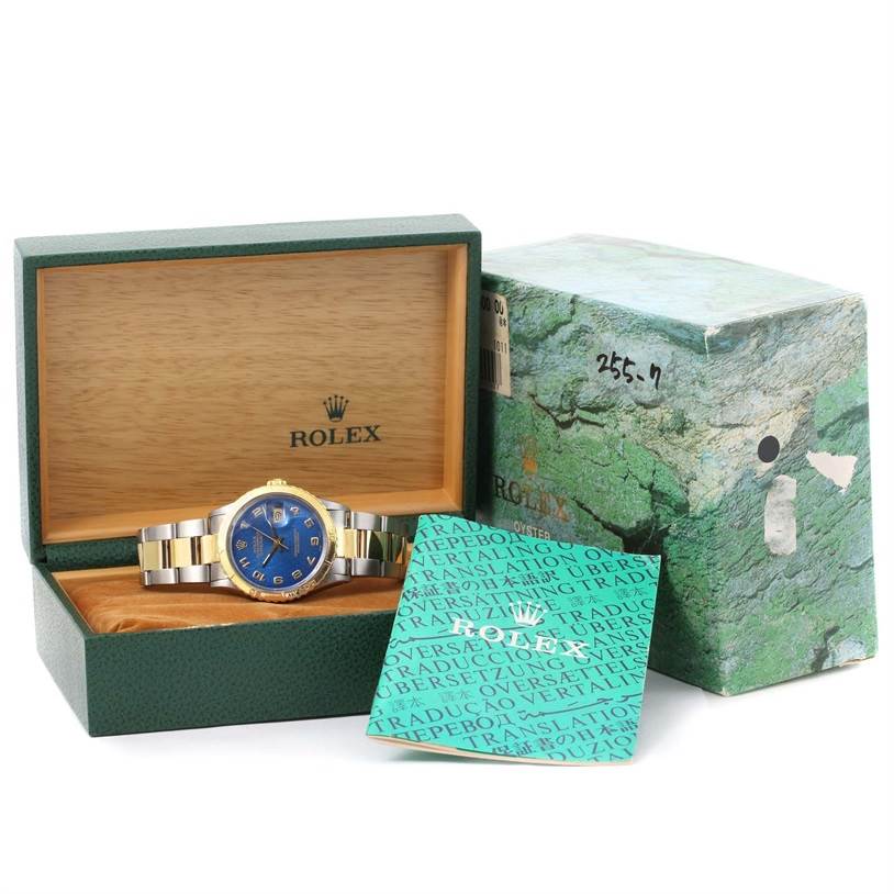 The Turn-o-Graph Rolex watch is displayed front-on within an open green Rolex box, with the outer box and booklet also visible.