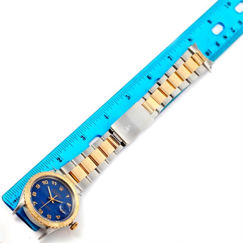 The image shows a Rolex Turn-o-Graph 16253 Men
s Steel and Gold (two tone) Blue Dial 16253 Men
s Steel and Gold (two tone) Blue Dial watch laid flat, with a blue ruler beside it for size comparison.