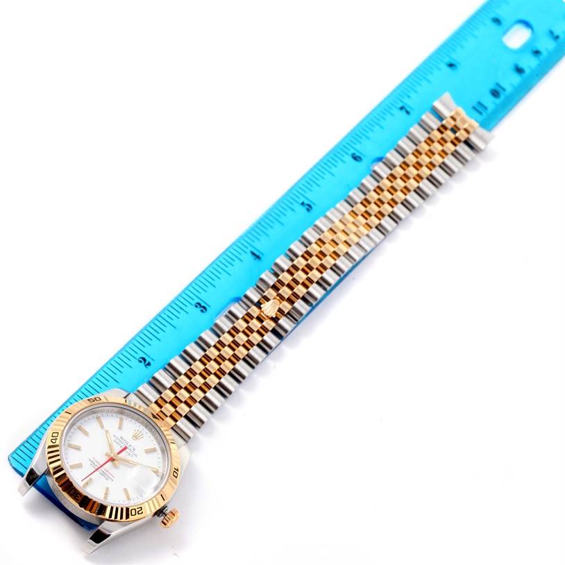 The Rolex Turn-o-Graph 116263 Men's Stainless Steel White Dial 116263 Men's Stainless Steel White Dial watch is shown from an angled top view, emphasizing its face, bezel, and two-tone bracelet alongside a ruler.