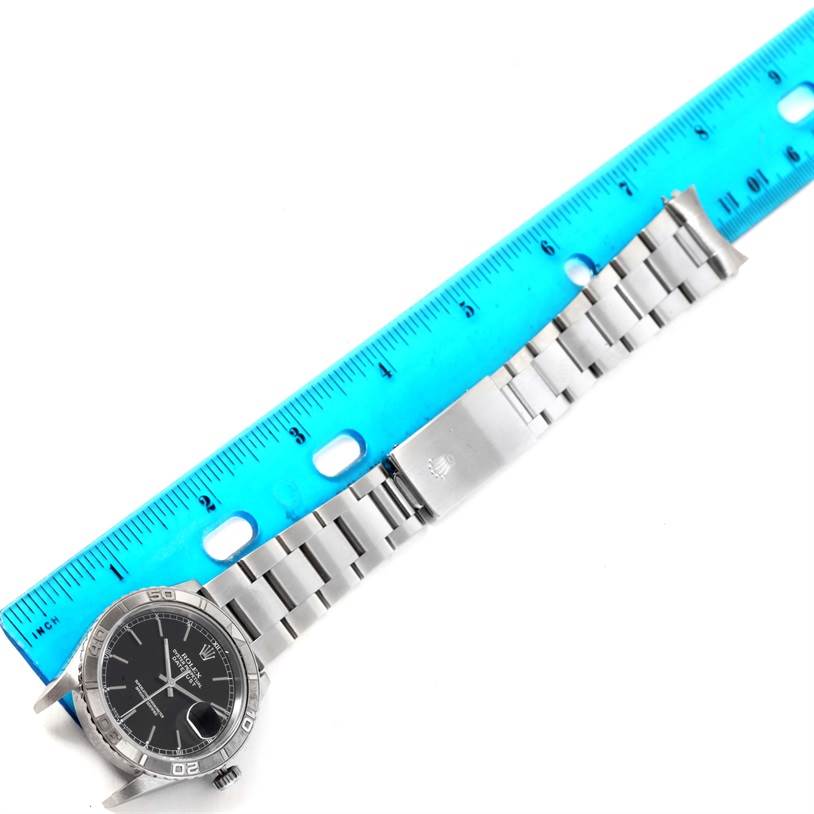 The image shows a top-down view of a Rolex Turn-o-Graph 16264 Men's Stainless Steel Black Dial 16264 Men's Stainless Steel Black Dial watch, featuring its dial, bezel, bracelet, and clasp, with a ruler for scale.