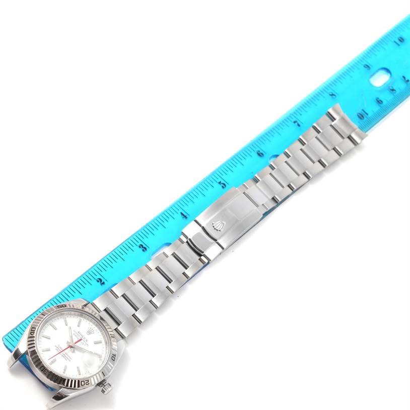 The image shows a side angle view of the Rolex Turn-o-Graph 116264 Men
s Stainless Steel White Dial 116264 Men
s Stainless Steel White Dial watch with its full metal bracelet placed next to a ruler.