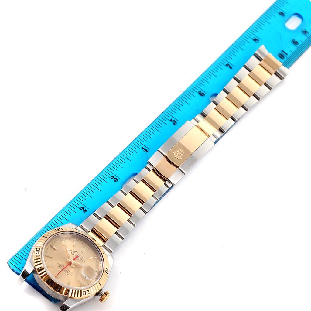 The Rolex Turn-o-Graph 116263 Men
s Stainless Steel Champagne Dial 116263 Men
s Stainless Steel Champagne Dial watch is shown laid flat with its dial, bezel, bracelet, and clasp visible alongside a measurement ruler.