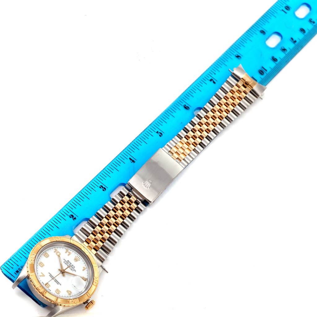 This image shows a top view of a Rolex Turn-o-Graph 16263 Men
s Steel and Gold (two tone) White Dial 16263 Men
s Steel and Gold (two tone) White Dial watch, including the face, bezel, and bracelet, alongside a blue ruler.