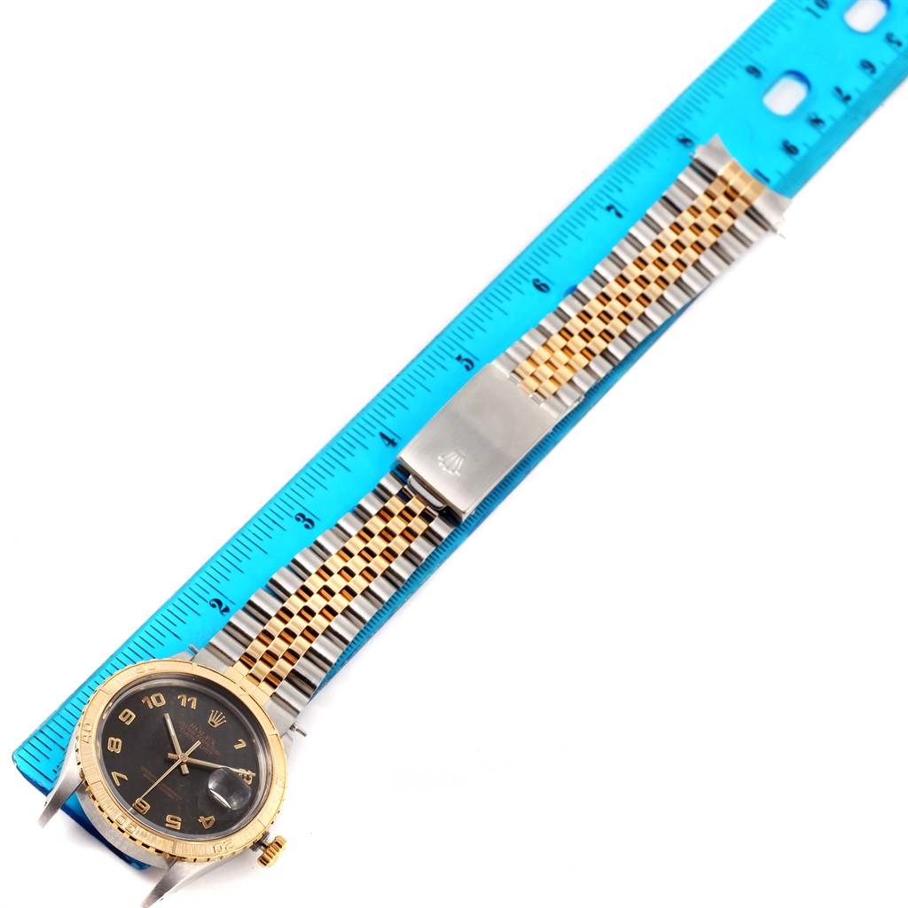 The image shows a Rolex Turn-o-Graph 16253 Men's Steel and Gold (two tone) Black Dial 16253 Men's Steel and Gold (two tone) Black Dial watch laid flat, fully displaying its face, bezel, bracelet, and clasp next to a blue ruler.