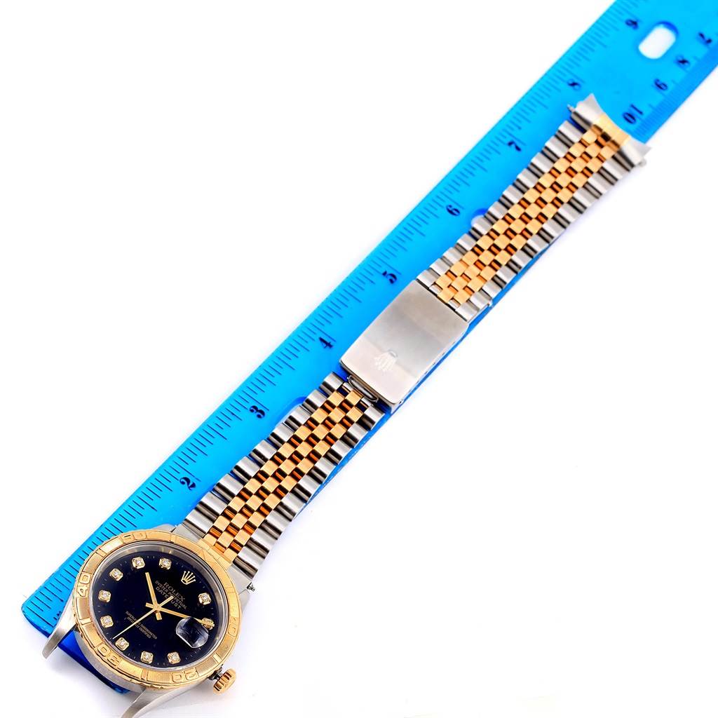 The Rolex Turn-o-Graph 16263 Men
s Steel and Gold (two tone) Black Dial 16263 Men
s Steel and Gold (two tone) Black Dial watch is shown from a top-down angle, with its face, bezel, and two-tone bracelet visible next to a ruler.