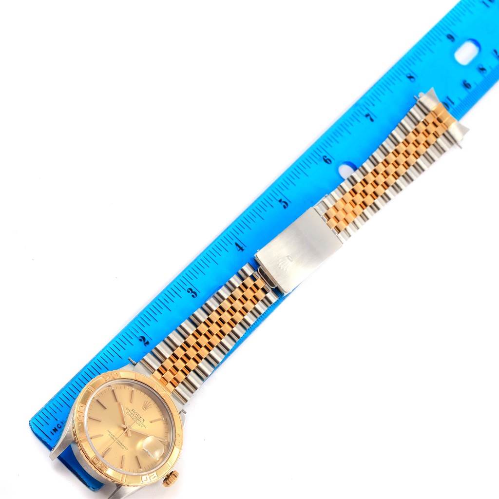 A top-down view of the Rolex Turn-o-Graph 16263 Men
s Steel and Gold (two tone) Champagne Dial 16263 Men
s Steel and Gold (two tone) Champagne Dial watch showing the face, bezel, and full bracelet placed against a blue ruler.