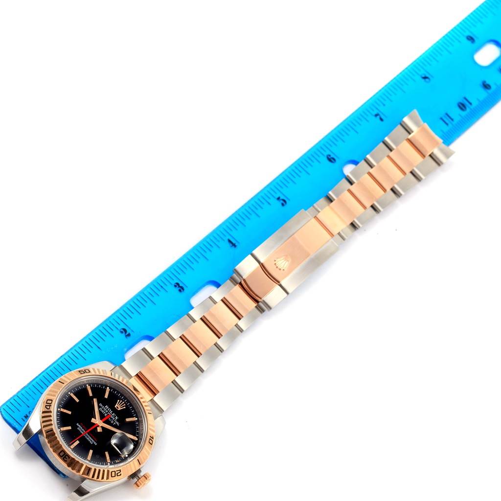 The image shows a Rolex Turn-o-Graph 116261 Men's Stainless Steel Black Dial 116261 Men's Stainless Steel Black Dial watch laid flat next to a ruler, highlighting its bracelet and clasp.